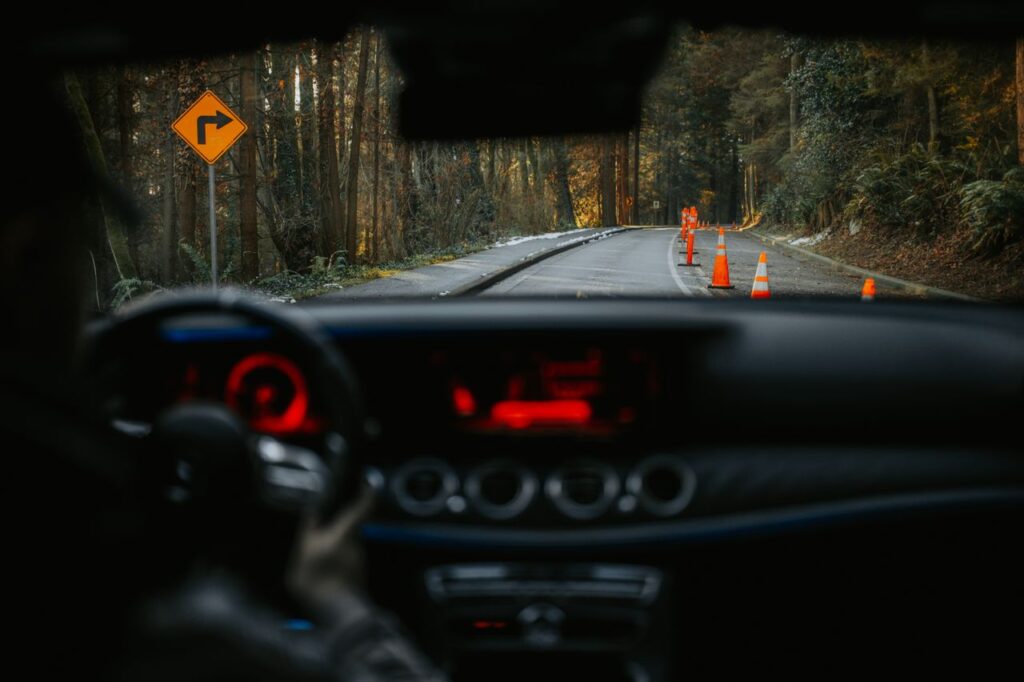 The Art of Drawing Readers In: Your attractive post title goes here View from car dashboard of rural road with traffic cones and turn sign. Scenic forest driving experience.