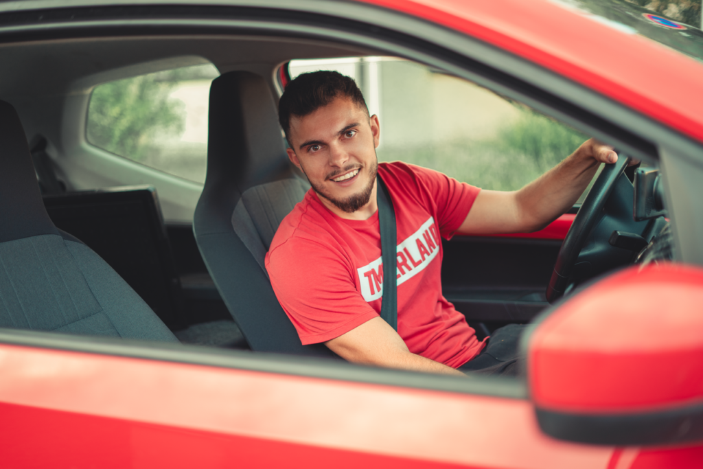 Mastering the First Impression: Your intriguing post title goes here Smiling man driving a red car while wearing a seatbelt, showcasing safety and joy.