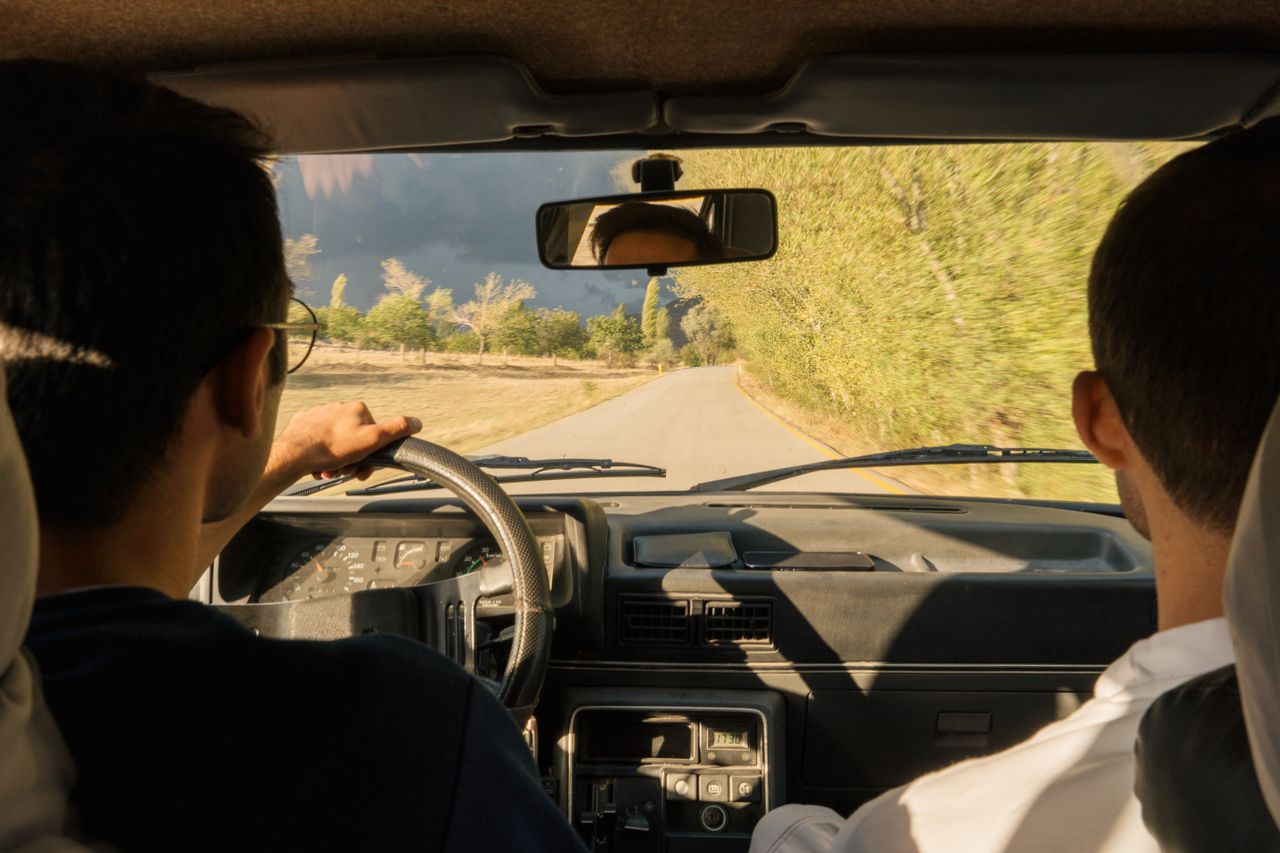 Crafting Captivating Headlines: Your awesome post title goes here Two adults driving through scenic countryside near Merzifon, Türkiye, in a vintage car.